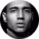 Close-up portrait of a young man with dark skin and short hair wearing a black shirt.